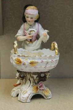 a porcelain figurine of a girl holding a bird in a basket on top of a table