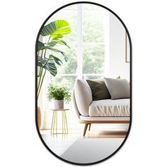 a living room with a couch and potted plant in the corner, as well as a large oval mirror