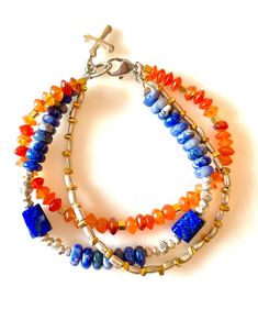 Trio of beaded bracelets featuring lapis lazuli, denim blue sodalite and carnelian and Karen Hill Tribe fine silver and gold vermeil. One strand is natural orange carnelian translucent faceted 6mm rondelles accented with Karen Hill Tribe 24k gold vermeil cubes. A second strand is shades of denim and cobalt blue 6.5mm smooth sodalite rondelles and deep blue lapis lazuli free form tube beads accented smith Karen Hill Tribe .999 fine silver faceted cubes and flower beads. Third strand is silver and Sapphire Lapis Lazuli Beaded Bracelets, Sapphire Lapis Lazuli Gemstone Beaded Bracelets, Blue Lapis Lazuli Gemstone Beaded Bracelet, Sapphire Gemstone Beads Bracelet In Lapis Lazuli, Adjustable Lapis Lazuli Beaded Bracelets With Gemstone, Spiritual Sapphire Beaded Bracelets With Natural Stones, Spiritual Blue Lapis Lazuli Beaded Bracelets, Blue Lapis Lazuli Beaded Bracelets With Polished Beads, Blue Lapis Lazuli Bracelets With Polished Beads