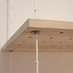 a light fixture hanging from a ceiling with white cords and wood planks on it