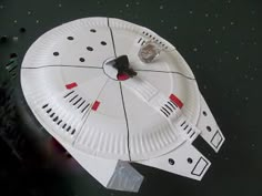 a paper plate that is shaped to look like a spaceship with red and black dots