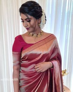 a woman in a red and gold sari with her hand on her hip, looking down