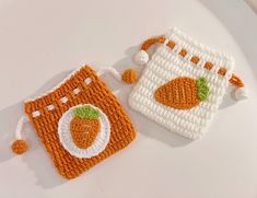 two crocheted carrots are sitting next to each other on a white surface