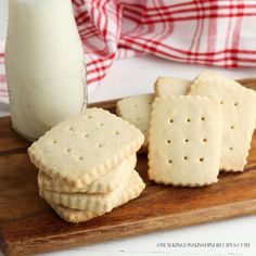 crackers on a cutting board next to a glass of milk