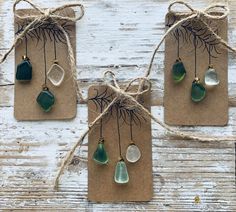 four pieces of sea glass hanging from twine on brown paper with twine and twine