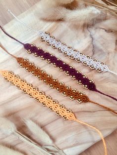 four beaded bracelets sitting on top of a fur covered table next to feathers