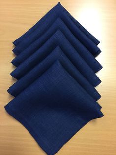 six blue napkins sitting on top of a wooden table