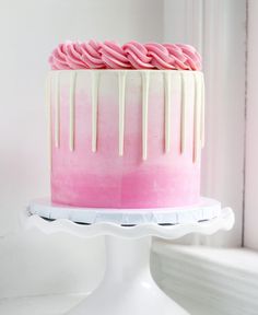 a pink and white cake with icing drizzled on it's side