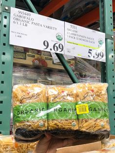 some pasta is being held up by someone's hand in a grocery store aisle