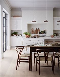 a kitchen with white cabinets and wooden table surrounded by chairs in front of an oven