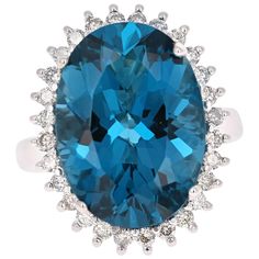 This beautiful Oval cut Blue Topaz and Diamond ring has a stunningly large Blue Topaz that weighs 13.62 Carats. It is surrounded by 28 Round Cut Diamonds that weigh 0.57 Carats. The total carat weight of the ring is 14.19 Carats. The setting is crafted in 14K White Gold and weighs approximately 7.0 grams. The ring is a size 6 and can be resized at no charge! Luxury White Topaz Round Ring, Luxury Blue Gemstones With Halo Setting, Oval Blue Topaz Diamond Ring For Formal Occasions, Luxury Blue Topaz Ring With Brilliant Cut, Oval Blue Topaz Diamond Ring With Brilliant Cut, Oval Sapphire Topaz Ring With Diamond Accents, Luxury Blue Oval Diamond Ring, Elegant Blue Oval Topaz Ring, Blue Topaz Oval Diamond Ring