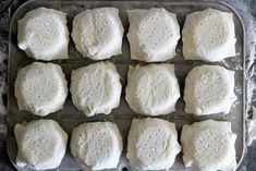 eight uncooked pizza doughs on a baking sheet ready to go into the oven