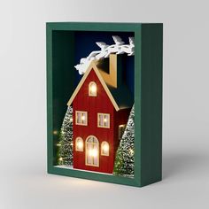 a christmas card with a red house in the middle and white birds flying over it