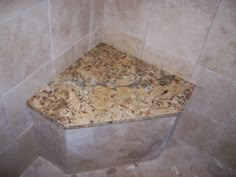 a marble shower stall in a bathroom with tile walls and flooring that looks like granite