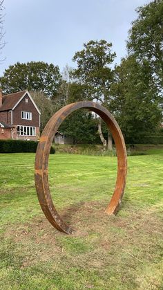 a large metal sculpture in the middle of a field with a house in the background