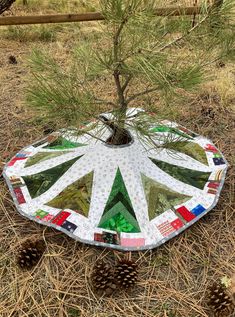 a patchwork christmas tree skirt made out of scrapbook pages is shown in the middle of a field with pine cones