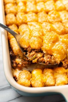 a spoon full of tater tot casserole with meat and cheese