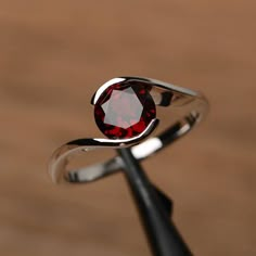 a close up of a ring with a red stone in it on a wooden surface