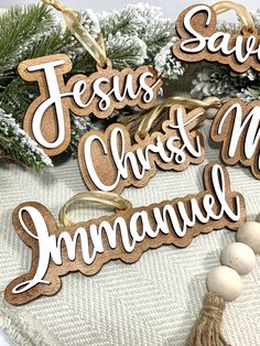 wooden christmas ornaments with the words jesus christ and his name on them, surrounded by pine branches