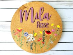 a wooden sign that says mela rose with flowers painted on the front and side