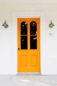 an orange front door with two lights on each side and one light on the other