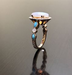 a ring that is sitting on top of a black surface with blue and yellow stones