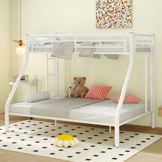 a white bunk bed with a teddy bear sitting on the bottom and underneath it in a room