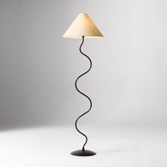 a floor lamp with a white shade on it's side and a black base