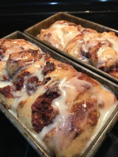 two pans filled with cinnamon rolls covered in icing