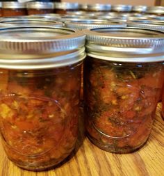 four jars filled with food sitting on top of a wooden table