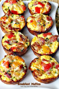 breakfast muffins with tomatoes and cheese are on a white platter, ready to be eaten