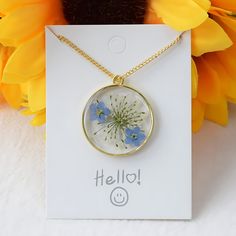 a necklace with blue flowers on it sitting next to yellow flowers