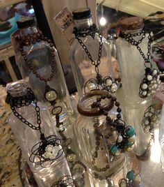 several glass bottles with necklaces in them on a table