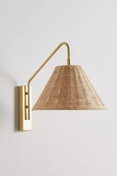 a wall light with a woven shade on the side and a metal arm, against a white background