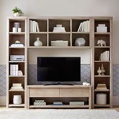 an entertainment center with bookshelves, shelves and a tv on top of it