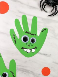 handprinted halloween craft for kids with eyes and mouth on marble surface next to spider