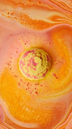 an orange and yellow substance in the center of a pink liquid filled with red dots