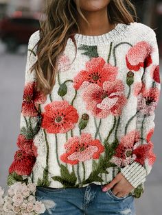 a woman wearing a white sweater with red flowers on it