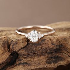 a white diamond ring sitting on top of a piece of driftwood with the background