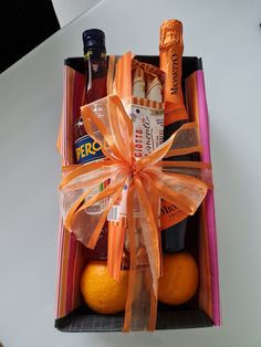 an open box with oranges, bottles and condiments wrapped in ribbon on top