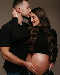 a pregnant couple cuddles and kisses their belly