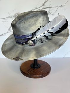 This is a gorgeous stiff brim painted fedora accented with purple, silver, and black colors. This hat is a size large with an elastic inner band for the most comfortable fit. Please see size chart in the pictures. Adjustable Fedora With Feather Trim For Kentucky Derby, Adjustable Wide Brim Purple Fedora, Adjustable Purple Brimmed Fedora, Adjustable Purple Fedora With Short Brim, Purple Adjustable Short Brim Fedora, Adjustable Silver Fedora Hat, Adjustable Purple Short Brim Fedora, Silver Adjustable Hat With Short Brim, Adjustable Purple Hat With Feathers