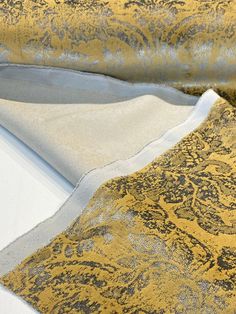 a yellow and grey fabric with black designs on the side, laying flat against a white background