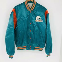 Vintage Swingster Large Miami Dolphins Snap Button Satin Football Jacket USA Nylon Size: Large Materials: Nylon/Polyester Features: Vintage made in USA, quilted lining, snap buttons, knit collar and cuffs. Condition: Gently worn, no flaws or defects Measurements taken while laying flat: Shoulders: 23 Chest: 26 Waist: 17 at knit waist (Stretches) Length: 26 Sleeve: 24 Storage Code: RACK 60 Please use the measurements above to compare with something in your wardrobe that fits well. Vintage Outerwear With Button Closure For College, Vintage Denim Jacket With Snap Buttons And Collar, Vintage Green Long Sleeve Sport Coat, Vintage Nylon Outerwear For Sports, Green Vintage Outerwear With Snap Buttons, Vintage Green Outerwear With Snap Buttons, Vintage Nylon Sports Outerwear, Football Jacket, Vintage Snap Button-up Tops