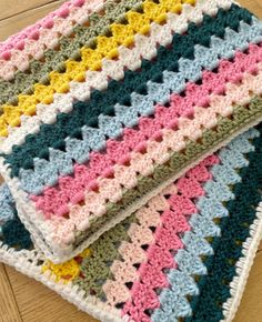 two crocheted blankets sitting on top of a wooden floor