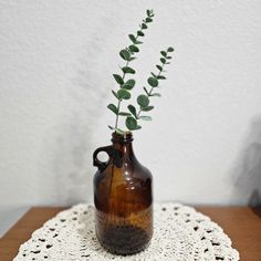 a vase with a plant in it sitting on a doily