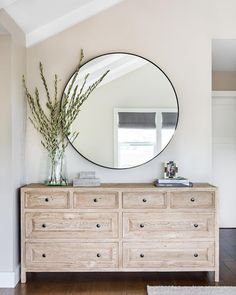 a white dresser with a round mirror above it and an instagram button on the bottom