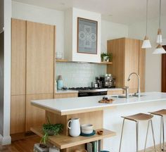 a kitchen with wooden cabinets and white counter tops, two stools on each side