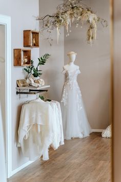 wedding gowns are on display in a bridal room with flowers hanging from the ceiling