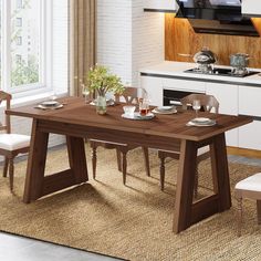 a dining room table with chairs and a television on the wall in the kitchen area